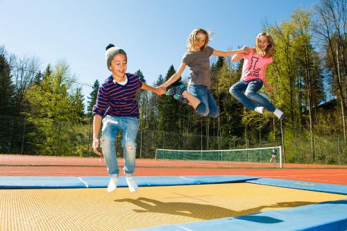 three girls jumping in the air on a trampoline at MONDI Resort und Chalet Oberstaufen in Oberstaufen