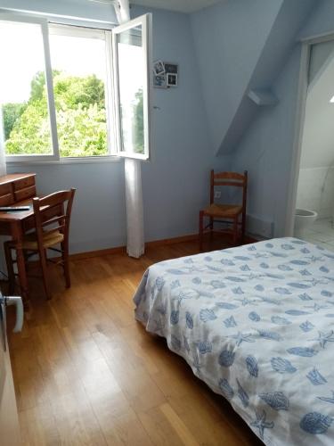 a bedroom with a bed and a table and a window at la Bergerie in Tréméreuc