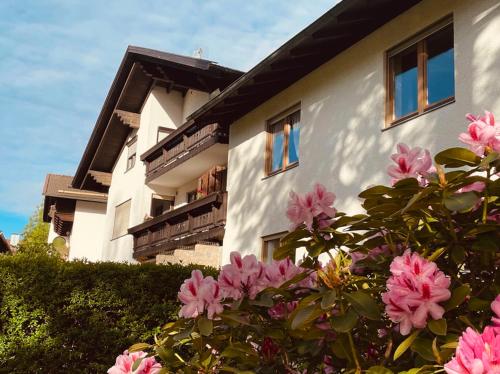 un edificio con flores rosas delante de él en Ferienwohnungen Irmengard, en Bernau am Chiemsee