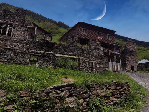 an old stone building with a moon in the sky at Raul Lushnu Darbaz in Mestia