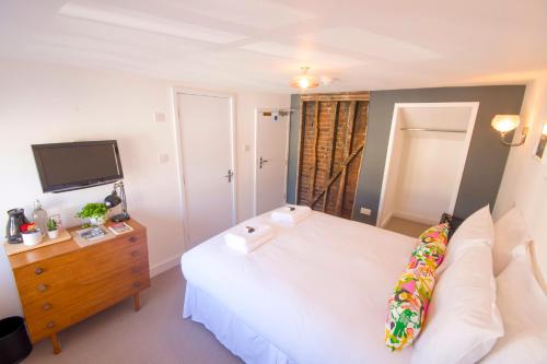 a bedroom with a white bed and a tv at Dog and Whistle Pub in Hertford