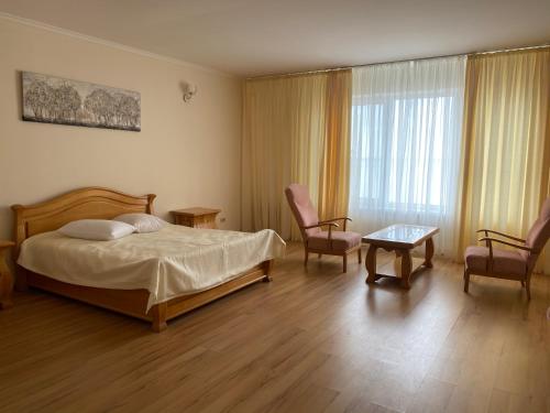 1 dormitorio con 1 cama, 2 sillas y ventana en Hotel DA NONNA en Odesa