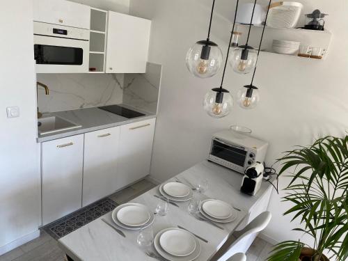- une cuisine blanche avec une table et des plaques de cuisson dans l'établissement La Fleur Marine Classé 3 étoiles - Accès direct mer Cabourg, à Cabourg