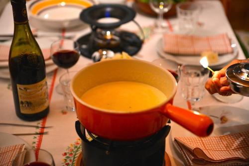 a pot of soup sitting on a table with a bottle of wine at Chesa Panorama in Celerina