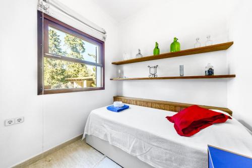 a bedroom with a bed and a window and shelves at Sa Rota de l'Avi - Can Colombas in La Aranjasa