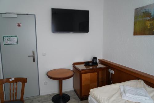 a room with a bed and a table and a television at Budget Boarding House Weidenberg in Weidenberg