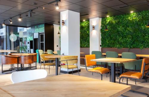Un restaurante con mesas, sillas y plantas. en Vértice Roomspace, en Madrid