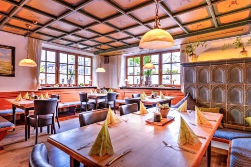 ein Restaurant mit Holztischen, Stühlen und Fenstern in der Unterkunft Zur Post Kümmersbruck Hotel & Tiny Houses in Kümmersbruck