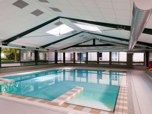 uma grande piscina com tecto aberto em Aparthotel Adagio Val d'Europe près de Disneyland Paris em Serris