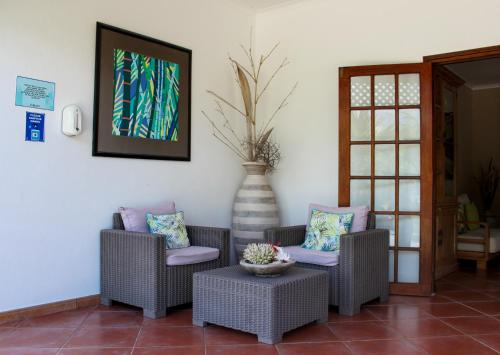 a living room with two chairs and a table and a vase at L'Habitation Cerf Island in Cerf Island