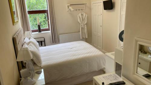 a white bedroom with a bed and a window at Bridge Farm Hotel in Leeds