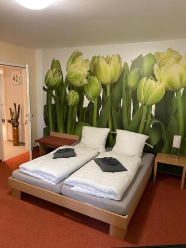 ein Bett mit einem Blumenbild an der Wand in der Unterkunft Ho(s)tel Ahrbergen in Giesen