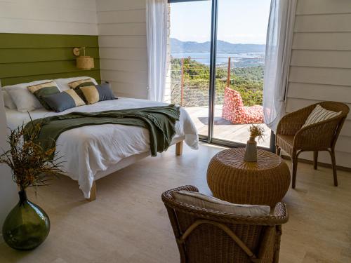 um quarto com uma cama e uma grande janela em Villa L'Arbousière em Porto-Vecchio