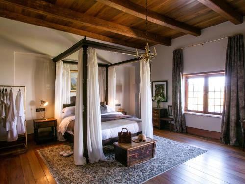 a bedroom with a canopy bed with a wooden ceiling at The Homestead at Hazendal, in Stellenbosch Winelands by NEWMARK in Stellenbosch