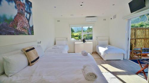 a white bedroom with two beds and a window at theLAB Robertson in Robertson