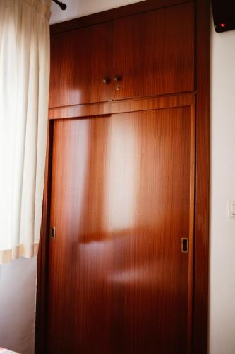 a wooden closet in a bedroom with a curtain at Hostal la Campana in Motril