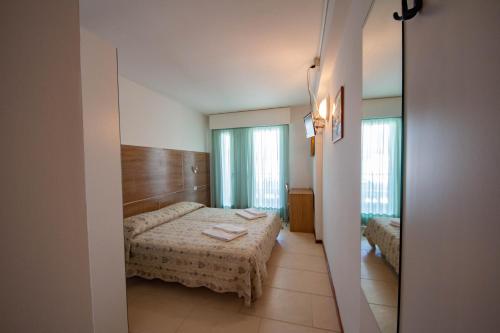 a small room with a bed and a mirror at Hotel Ambra in Lignano Sabbiadoro