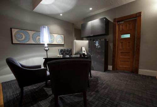 a room with a desk and chairs and a refrigerator at Le Pleasant Hôtel & Café in Sutton