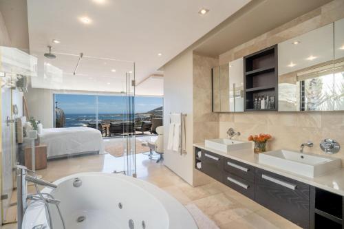 un bagno con vasca e 2 lavandini e una camera da letto di Azamara Luxury Villa - Camps Bay a Città del Capo