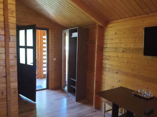 Habitación con paredes de madera, mesa y puerta. en Hanul Arcașului, en Voila