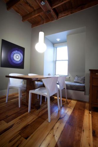a dining room with a table and white chairs at Le Pleasant Hôtel & Café in Sutton