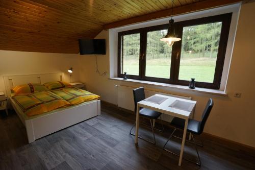 a bedroom with a bed and a table and a window at Brandthausen - Ferienwohnungen Familie Brandt in Heidersdorf