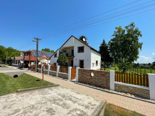 a white house with a fence in front of it at Kukorica Csárda Apartman in Balatonújlak
