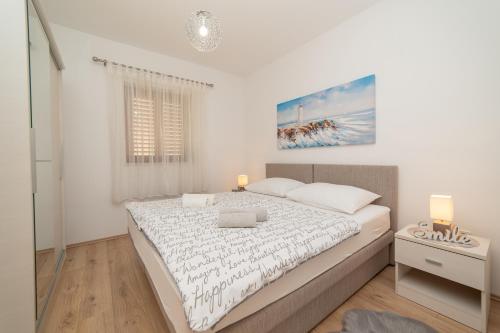 a white bedroom with a large bed and a window at Apartments Đivanović in Dubrovnik