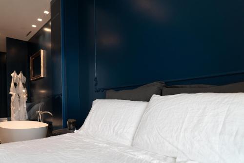 a bed with white sheets and a blue wall at PICCOLA MAESTA' boutique rooms in Civitanova Marche