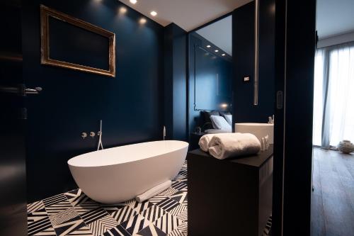 a bathroom with a large white tub and blue walls at PICCOLA MAESTA' boutique rooms in Civitanova Marche