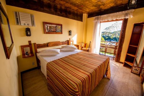 a bedroom with a bed and a large window at Pousada Monte Imperial in Petrópolis