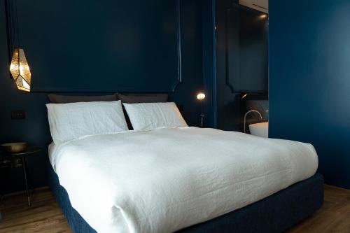 a bedroom with a large white bed with blue walls at PICCOLA MAESTA' boutique rooms in Civitanova Marche