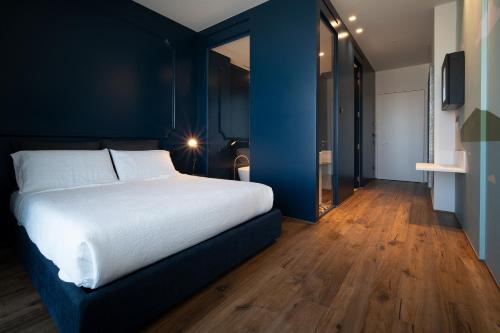 a bedroom with a white bed and a blue wall at PICCOLA MAESTA' boutique rooms in Civitanova Marche