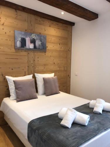 - une chambre avec un grand lit blanc et un mur en bois dans l'établissement Les appartements du Koifhus, à Colmar