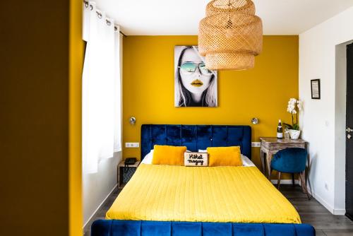 a yellow bedroom with a blue bed and yellow walls at Hôtel Eden Cassis - centre-ville- piscine chauffée, jacuzzi et sauna - parking privé in Cassis