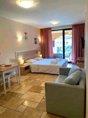 a bedroom with a bed and a couch and a table at Happy Studio Sea View in Topola
