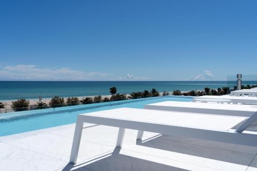 a white bench sitting next to a pool with the beach at PICCOLA MAESTA' boutique rooms in Civitanova Marche