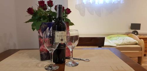 a table with two wine glasses and a vase with roses at NOCLEGI POD STODOŁĄ in Kraków