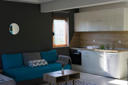Apartments Ena في تريبينيي: غرفة معيشة مع أريكة زرقاء ومطبخ
