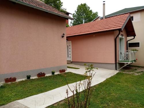 a house with a walkway next to a yard at Apartman TAJNA Vrdnik in Vrdnik