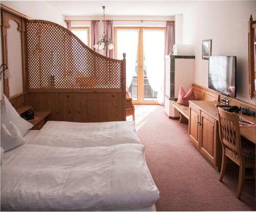 a bedroom with a bed and a desk and a television at Haus Feichtner in Reit im Winkl
