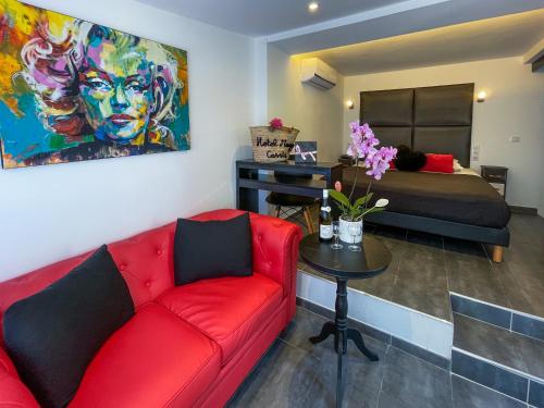 a living room with a red couch and a bed at Hôtel Eden Cassis - centre-ville- piscine chauffée, jacuzzi et sauna - parking privé in Cassis