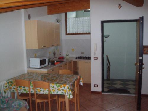 uma pequena cozinha com mesa e cadeiras e uma porta em Casa Osti em Spormaggiore