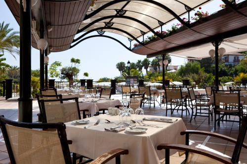 a restaurant with white tables and chairs and a roof at Gran Tacande Wellness & Relax Costa Adeje in Adeje