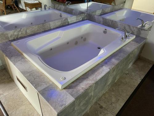 a large bath tub in a bathroom with a purple at VIBE INN - WHIRLPOOLS SUITES - Lyons in Lyons