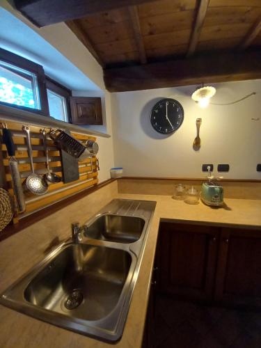 a kitchen with a sink and a clock on the wall at CASINA LA QUERCIA in Santa Sofia