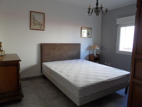 Schlafzimmer mit einem Bett mit weißer Bettwäsche und einem Fenster in der Unterkunft logement entre mer et montagne in Roujan