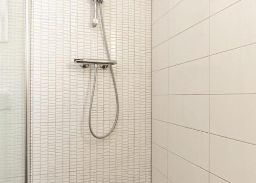 een douche in een badkamer met witte betegelde muren bij De Zandput 23 Zoutelande in Zoutelande