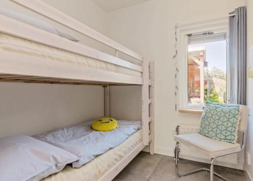een slaapkamer met een stapelbed met een geel kussen en een stoel bij De Zandput 23 Zoutelande in Zoutelande
