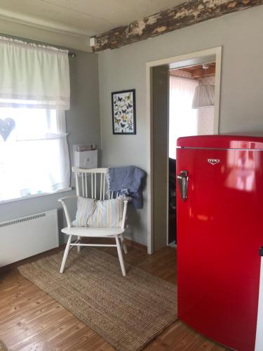 a red refrigerator in a room with a chair at Citymökki in Kristiinankaupunki